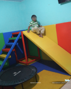 Anak kecil didalam ruang terapi bermain perosotan